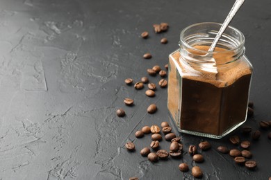 Photo of Instant coffee powder in jar and beans on dark textured table, closeup. Space for text
