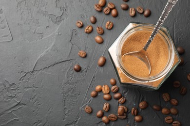 Photo of Instant coffee powder in jar and beans on dark textured table, flat lay. Space for text