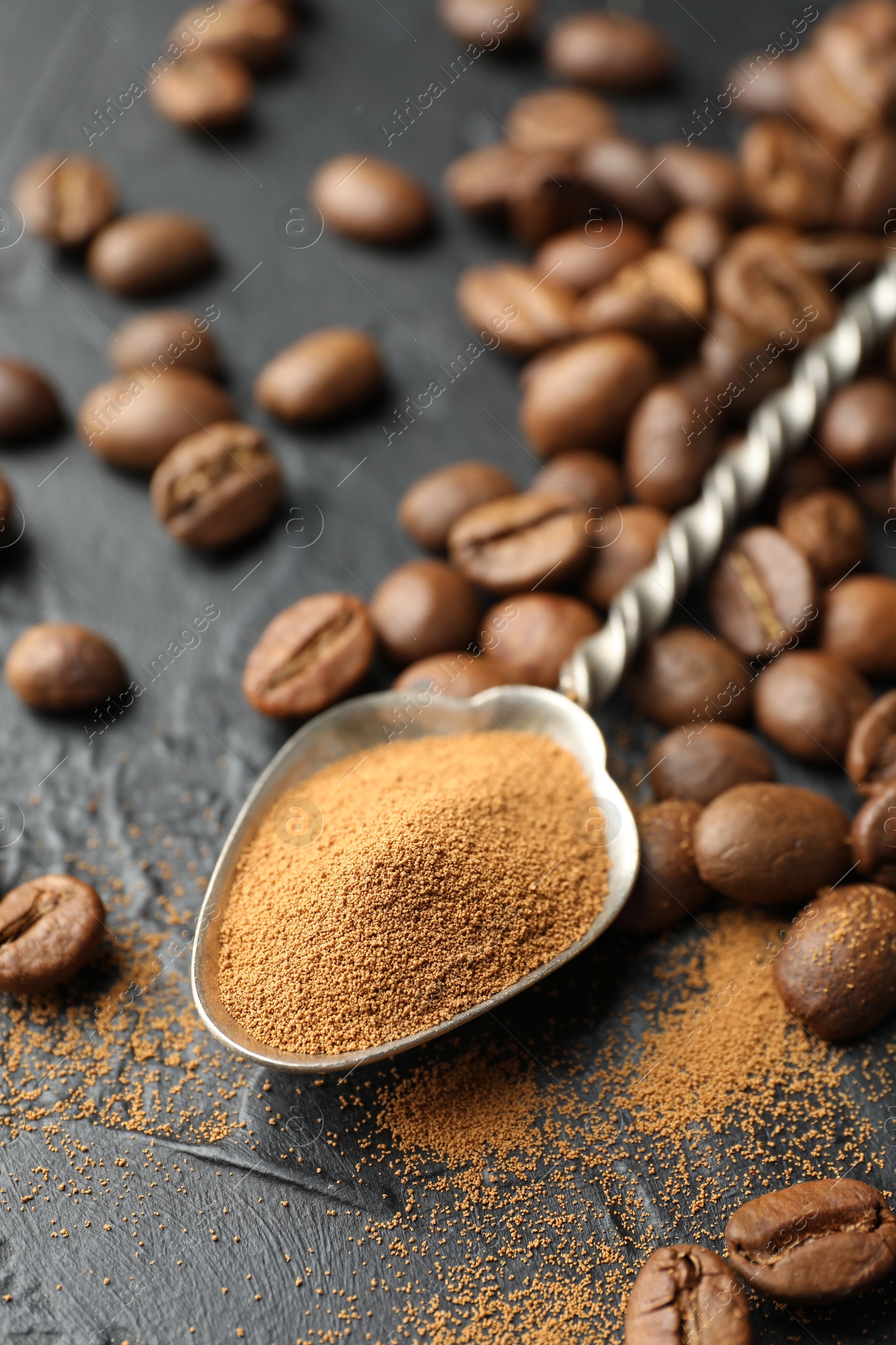 Spoon with instant coffee powder and beans on dark textured table, closeup Photo of Spoon with instant coffee powder and beans on dark textured table, closeup