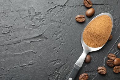 Photo of Spoon with instant coffee powder and beans on dark textured table, flat lay. Space for text