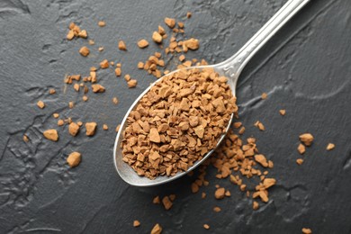 Photo of Spoon with granulated instant coffee on dark textured table, top view