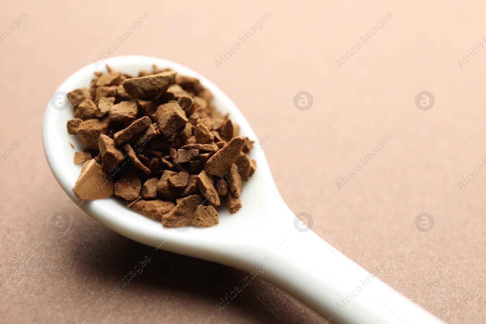 Spoon with granulated instant coffee on beige background, closeup Photo of Spoon with granulated instant coffee on beige background, closeup