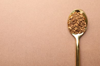 Photo of Spoon with granulated instant coffee on beige background, top view. Space for text