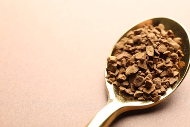 Photo of Spoon with granulated instant coffee on beige background, closeup. Space for text