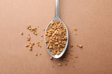 Photo of Spoon with granulated instant coffee on beige background, top view
