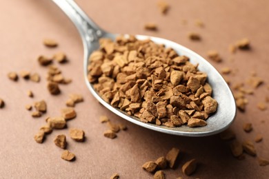 Photo of Spoon with granulated instant coffee on beige background, closeup