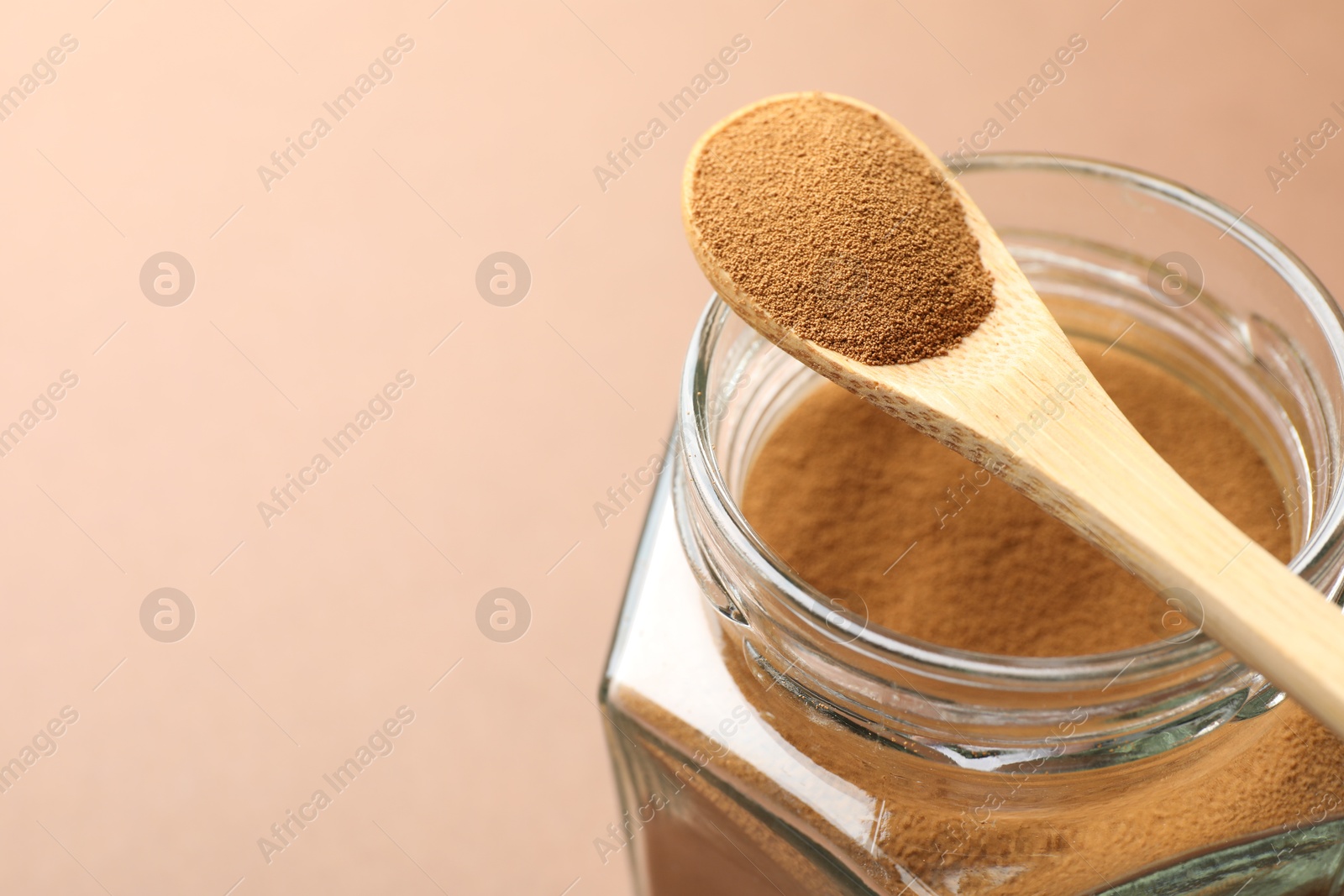 Spoon with instant coffee powder and jar on beige background, closeup. Space for text Photo of Spoon with instant coffee powder and jar on beige background, closeup. Space for text