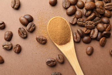 Photo of Spoon with instant coffee powder and beans on beige background, flat lay