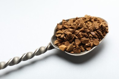 Photo of Spoon with granulated instant coffee on white background, closeup