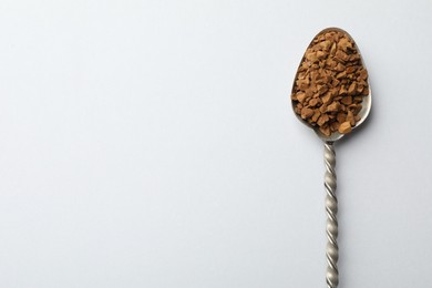 Photo of Spoon with granulated instant coffee on white background, top view. Space for text