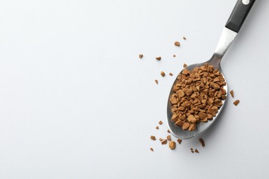 Photo of Spoon with granulated instant coffee on white background, top view. Space for text