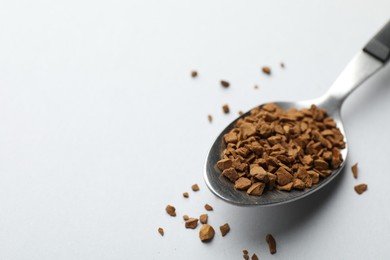Photo of Spoon with granulated instant coffee on white background, closeup. Space for text