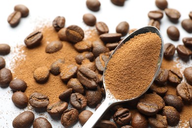 Photo of Spoon with instant coffee powder and beans on white background, closeup