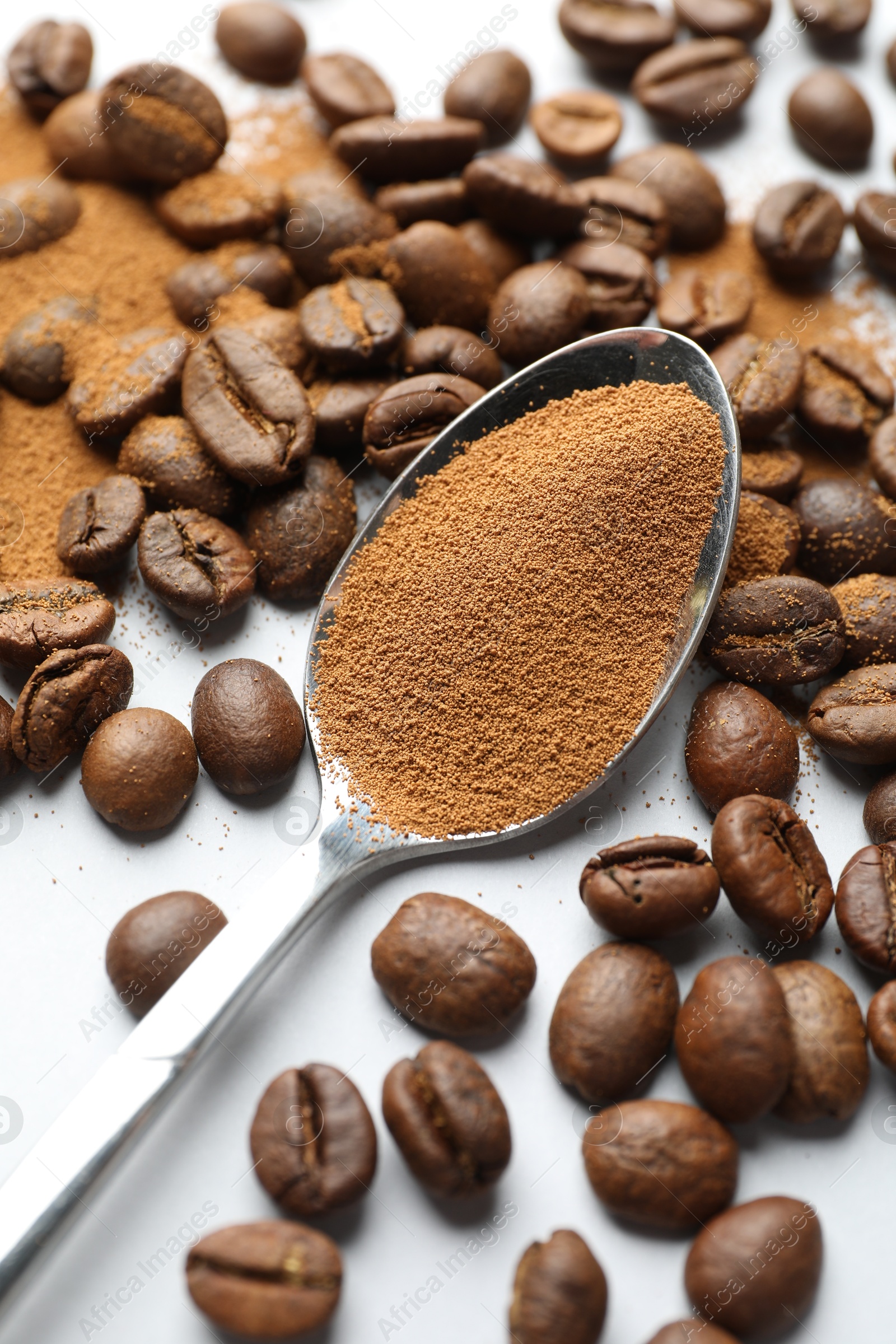 Spoon with instant coffee powder and beans on white background, closeup Photo of Spoon with instant coffee powder and beans on white background, closeup