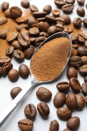 Photo of Spoon with instant coffee powder and beans on white background, closeup