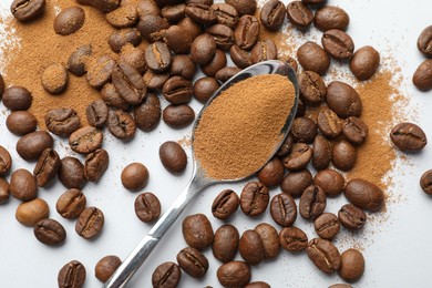 Photo of Spoon with instant coffee powder and beans on white background, flat lay