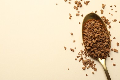 Photo of Spoon with granulated instant coffee on beige background, top view. Space for text
