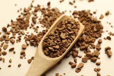 Photo of Spoon with granulated instant coffee on beige background, closeup