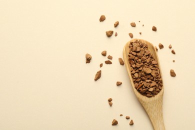 Photo of Spoon with granulated instant coffee on beige background, top view. Space for text