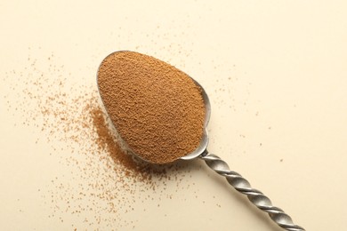 Photo of Spoon with instant coffee powder on beige background, top view