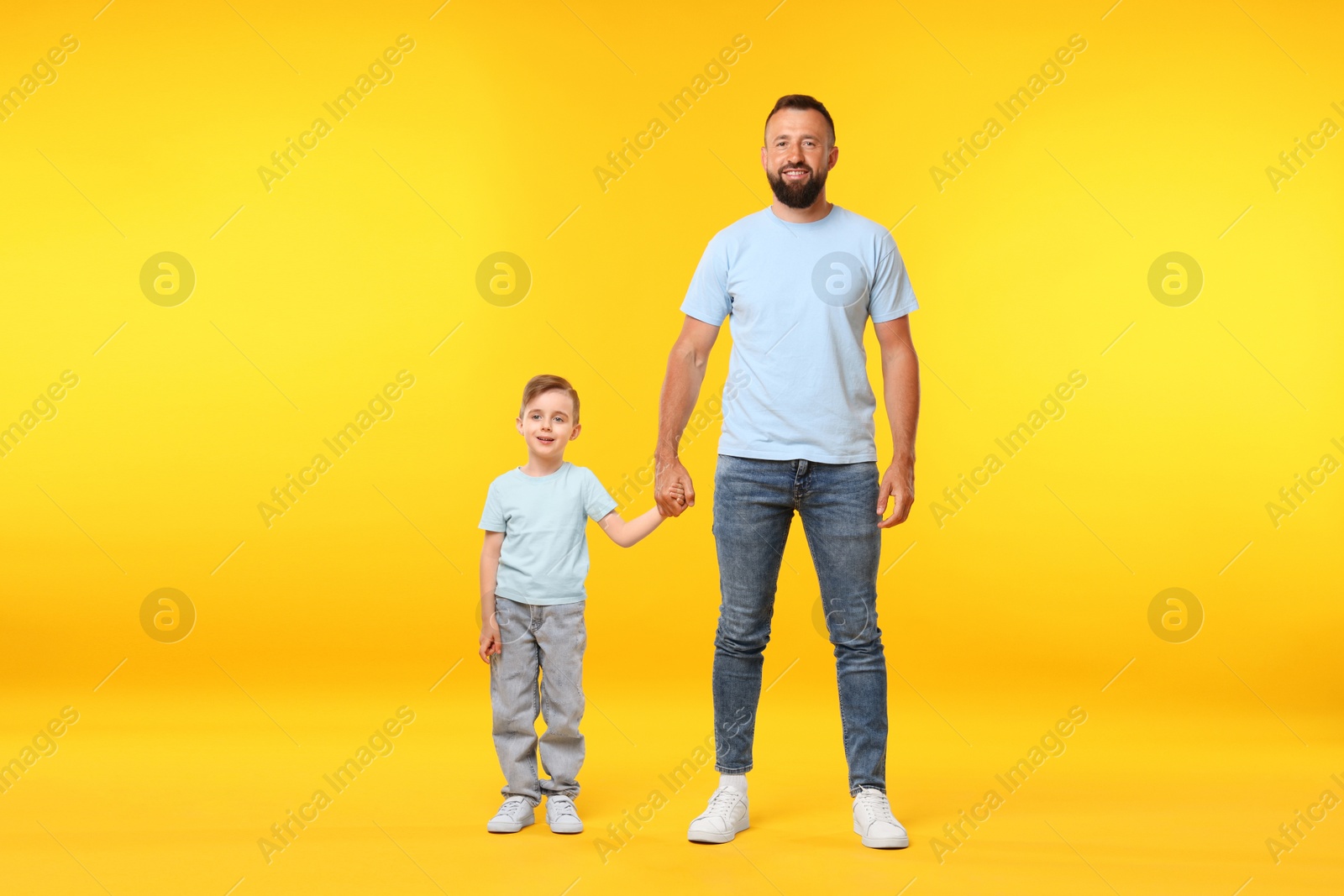 Family. Happy father and his son on yellow background Photo of Family. Happy father and his son on yellow background