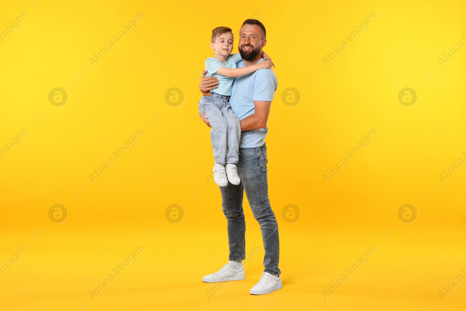 Family. Happy father and his son on yellow background Photo of Family. Happy father and his son on yellow background
