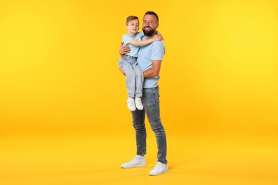 Photo of Family. Happy father and his son on yellow background