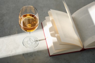 Photo of Glass of wine and book on grey table