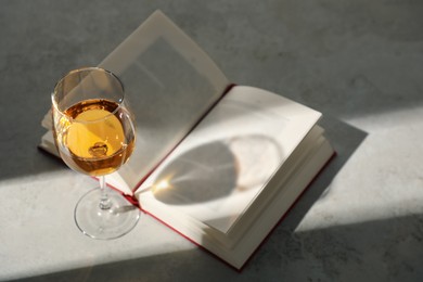 Photo of Glass of wine and book on grey table