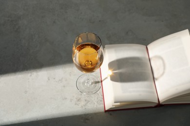 Photo of Glass of wine and book on grey table. Space for text
