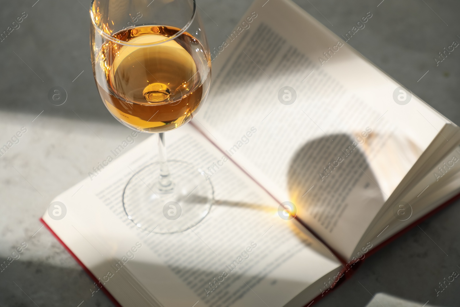 Photo of Glass of wine and book on grey table