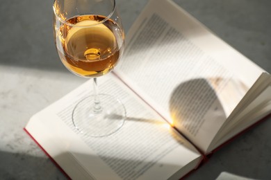Photo of Glass of wine and book on grey table