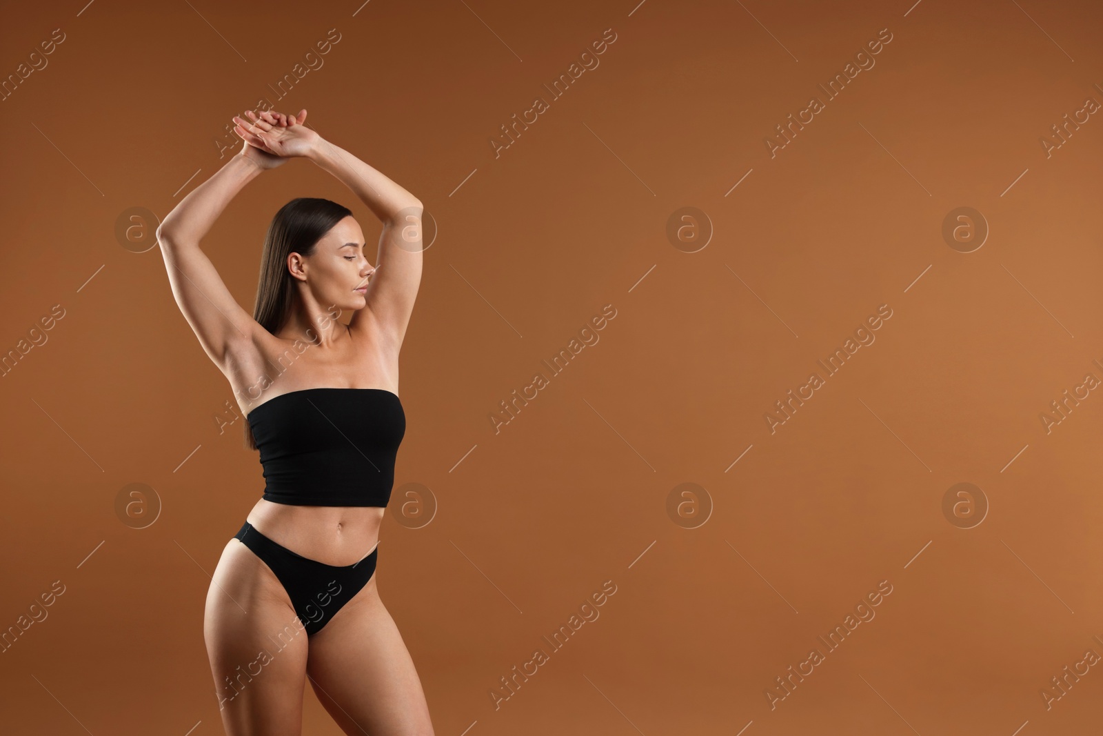 Fit woman with perfect body on brown background. Space for text Photo of Fit woman with perfect body on brown background. Space for text