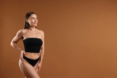 Photo of Fit woman with perfect body on brown background. Space for text
