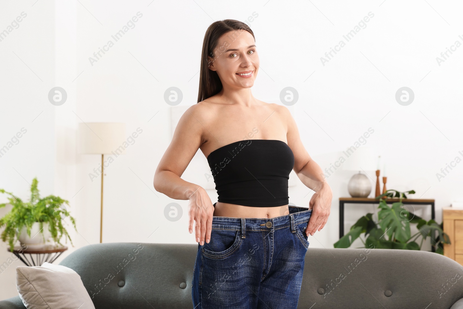 Fit woman wearing old jeans after weight loss at home Photo of Fit woman wearing old jeans after weight loss at home