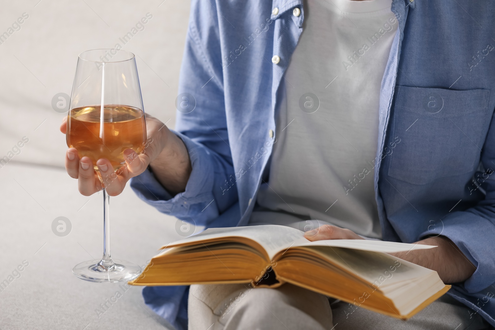 Woman with glass of wine reading book on sofa at home, closeup Photo of Woman with glass of wine reading book on sofa at home, closeup