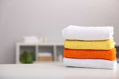Photo of Stack of colorful towels on white table indoors, space for text
