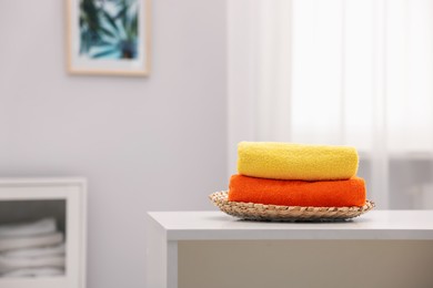 Photo of Stack of colorful towels on white table indoors, space for text