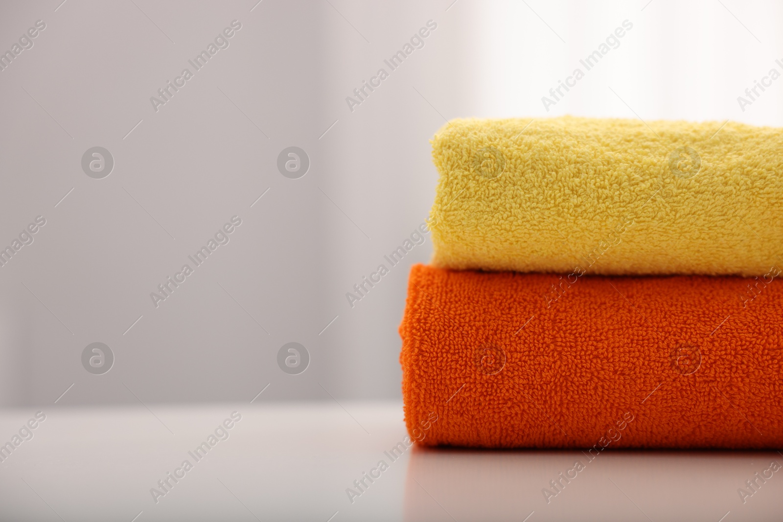 Stack of colorful towels on white table indoors, closeup. Space for text Photo of Stack of colorful towels on white table indoors, closeup. Space for text