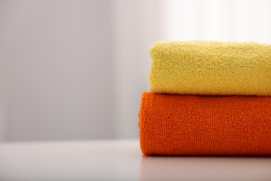 Photo of Stack of colorful towels on white table indoors, closeup. Space for text