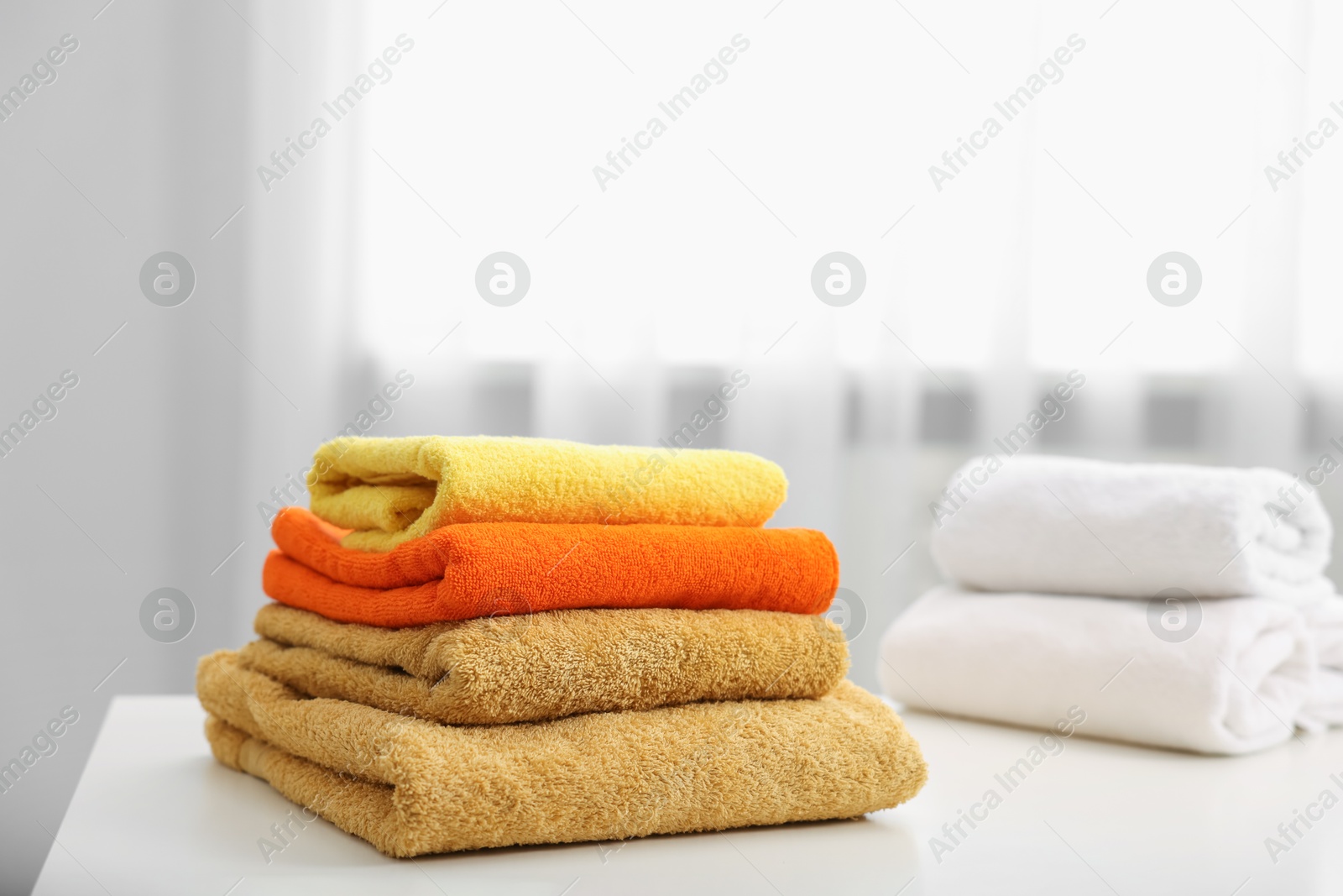 Stacks of colorful towels on white table indoors Photo of Stacks of colorful towels on white table indoors
