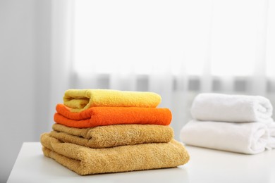 Photo of Stacks of colorful towels on white table indoors