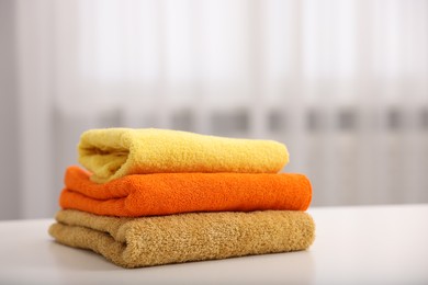 Photo of Stack of colorful towels on white table indoors, closeup