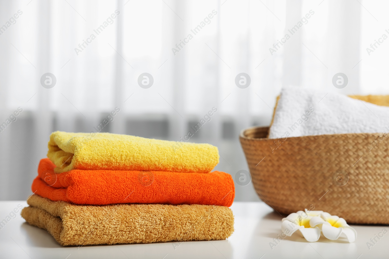 Colorful towels and plumeria flowers on white table indoors Photo of Colorful towels and plumeria flowers on white table indoors