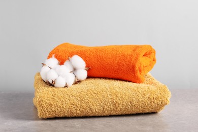 Photo of Colorful towels and cotton flowers on grey table, closeup