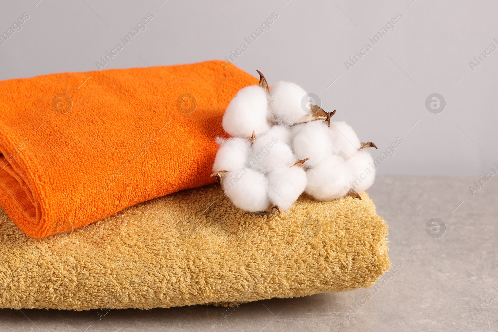 Colorful towels and cotton flowers on grey table, closeup Photo of Colorful towels and cotton flowers on grey table, closeup