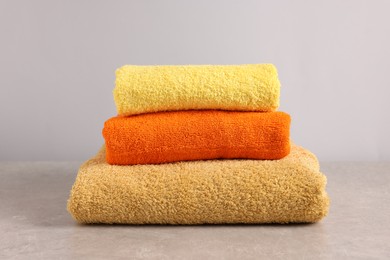 Photo of Stack of colorful towels on grey table, closeup