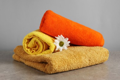 Photo of Colorful towels and chrysanthemum flower on grey table, closeup