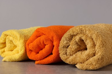 Photo of Rolled colorful towels on grey table, closeup
