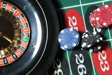 Photo of Casino chips and roulette wheel on table, flat lay